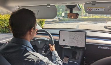 A driver drives a Tesla car on a city road
