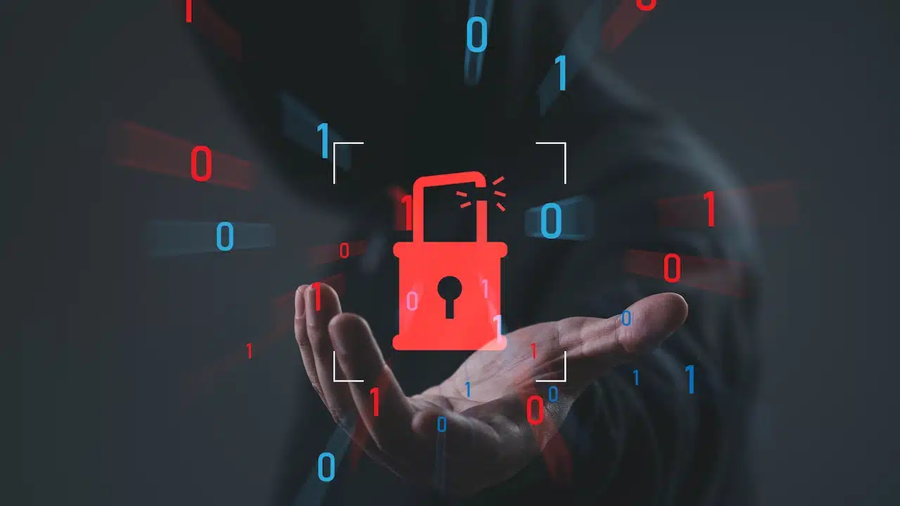 Cybersecurity breach concept with broken padlock and binary code over hooded hacker background, symbolizing data breach
