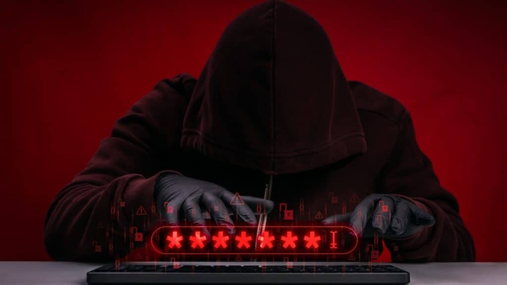 Hacker in hoodie stealing passwords by keyboard during cyberattack and data breach incident.