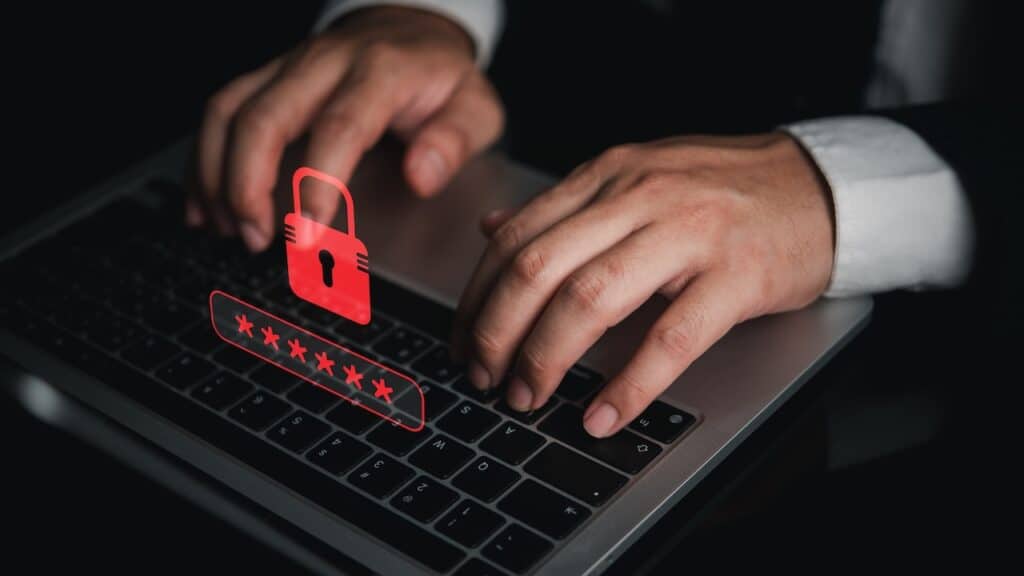 Businessman typing on laptop with red padlock and password graphic for cybersecurity data breach warning