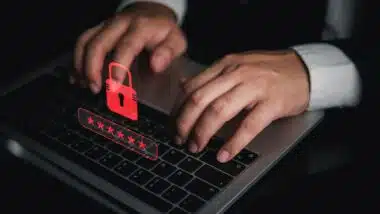 Businessman typing on laptop with red padlock and password graphic for cybersecurity data breach warning