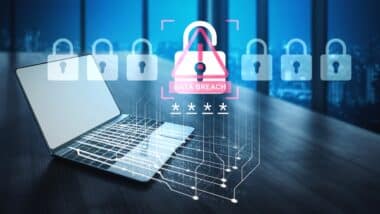 A laptop sits in a modern office, showcasing a digital alert for data breach with lock visuals, emphasizing cybersecurity and the importance of protecting sensitive information