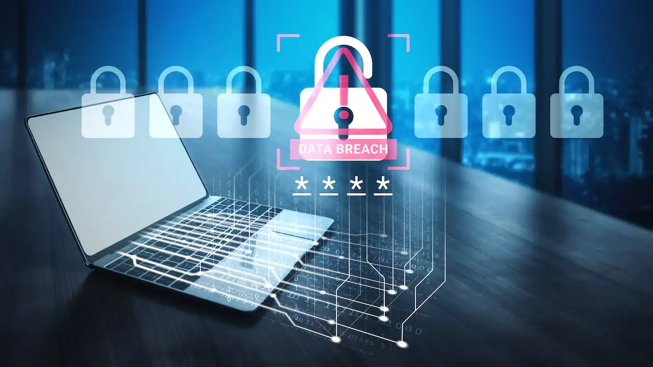 A laptop sits in a modern office, showcasing a digital alert for data breach with lock visuals, emphasizing cybersecurity and the importance of protecting sensitive information