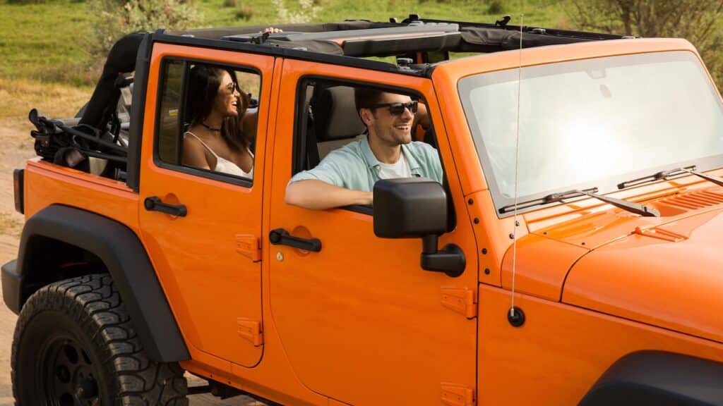Happy friends travelling together by a car