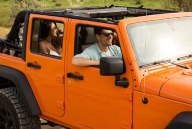 Happy friends travelling together by a car