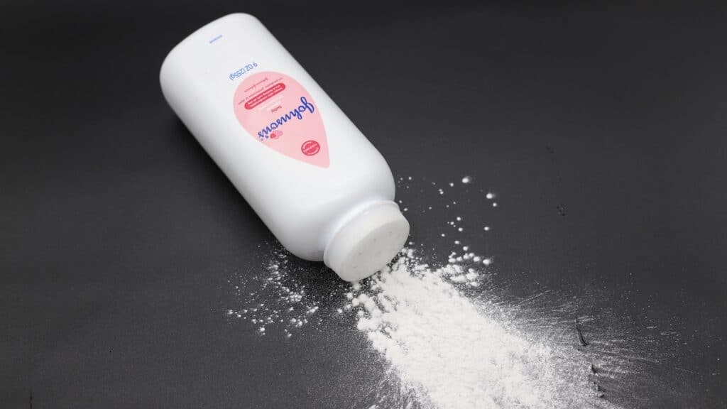 Close up image of white bottle of Johnson's baby powder isolated on black background.