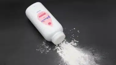 Close up image of white bottle of Johnson's baby powder isolated on black background.