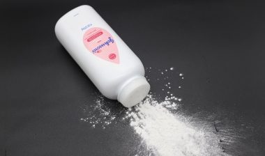 Close up image of white bottle of Johnson's baby powder isolated on black background.