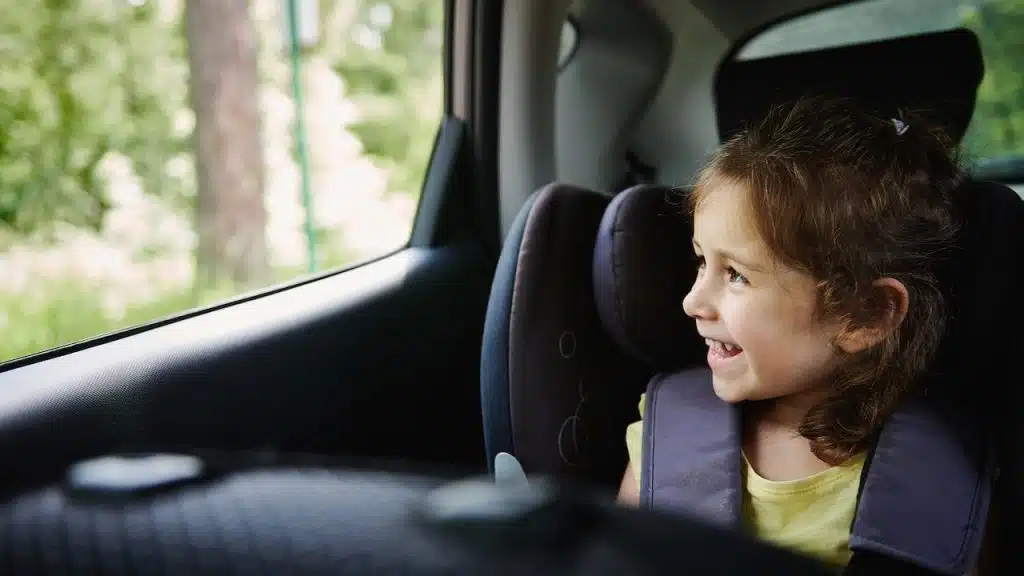 child in car seat looking out window of car