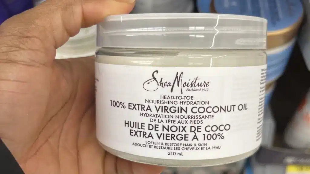 person holding a jar of SheaMoisture 100% Extra Virgin Coconut Oil