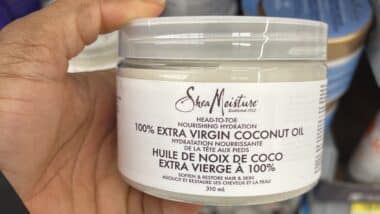 person holding a jar of SheaMoisture 100% Extra Virgin Coconut Oil