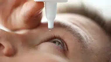 Male hand putting liquid drops in his eye