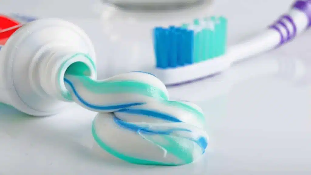 Toothbrush, tube of toothpaste and a glass on a white background
