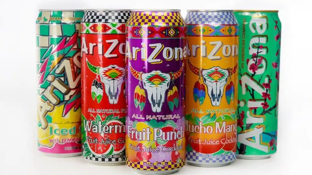 Vibrant arrangement of Arizona beverage cans featuring iced tea, watermelon, fruit punch, and much more on plain background.