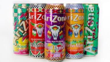 Vibrant arrangement of Arizona beverage cans featuring iced tea, watermelon, fruit punch, and much more on plain background.