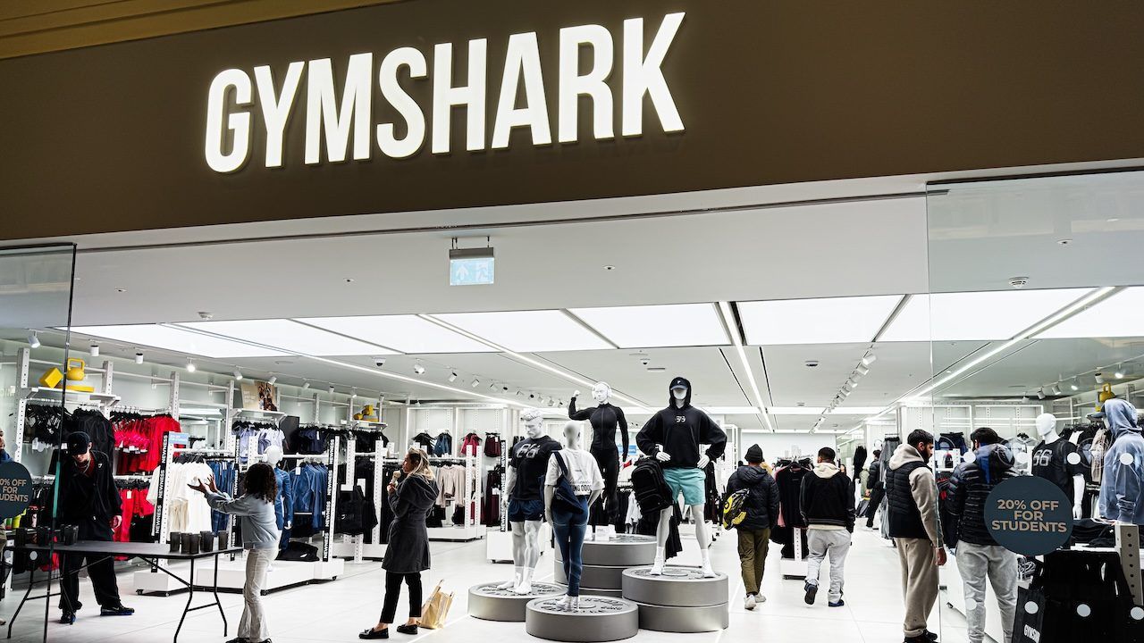 Inside the Gymshark shop, shoppers browse athleticwear around mannequins and bright lighting.