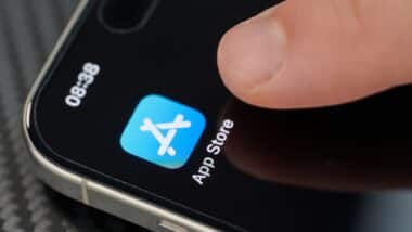 Touching top open App Store app icon with finger on iphone 15 pro max close up view