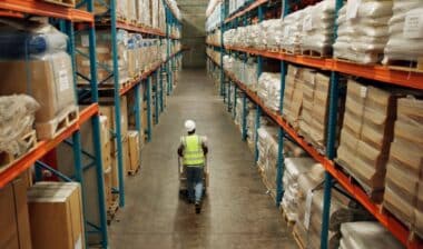 Almacén, envíos y un hombre caminando en una empresa de distribución, transporte de mercancías y cadena de suministro.