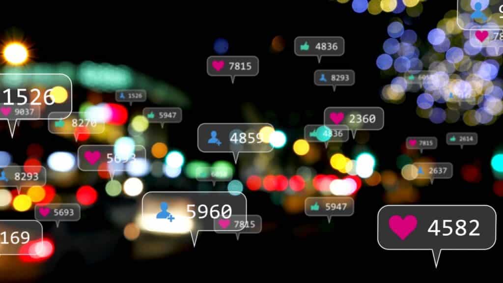 Image of social media icons and numbers over out of focus city lights.