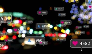 Image of social media icons and numbers over out of focus city lights.