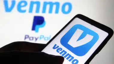 Venmo logo, a mobile payment service by Paypal, is displayed on a mobile phone screen and a monitor.