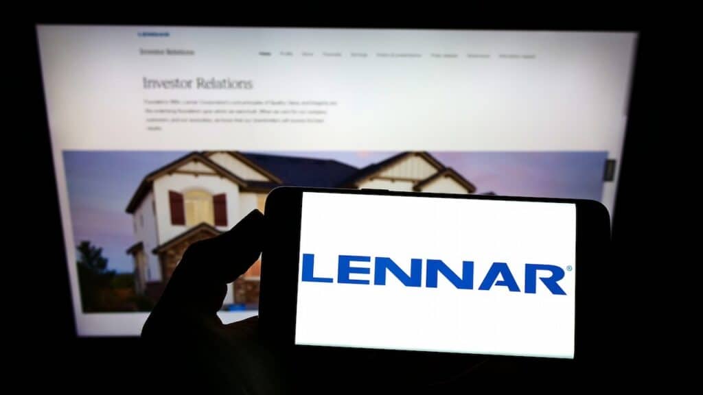 Person holding mobile phone with logo of US home construction company Lennar Corporation on screen in front of web page Focus on phone display