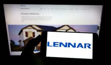 Person holding mobile phone with logo of US home construction company Lennar Corporation on screen in front of web page Focus on phone display