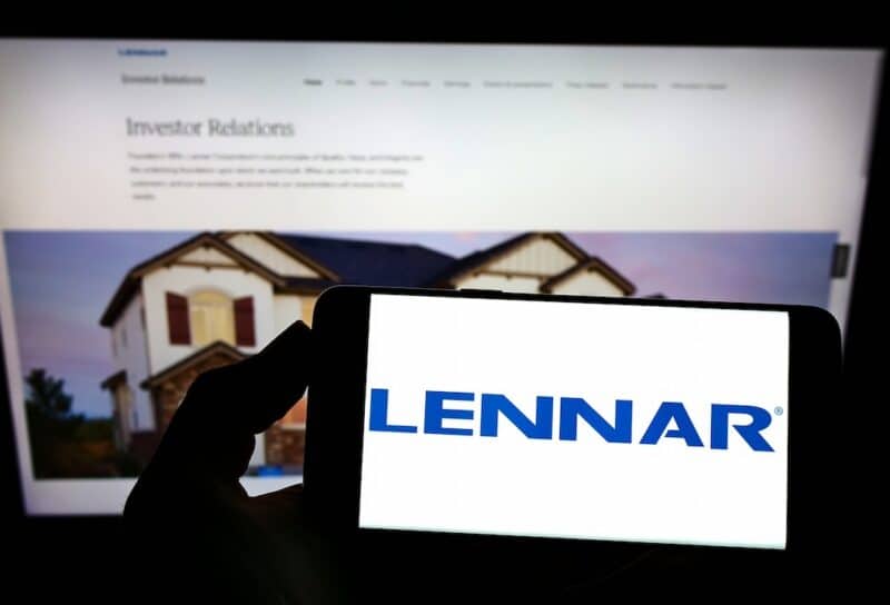 Person holding mobile phone with logo of US home construction company Lennar Corporation on screen in front of web page Focus on phone display