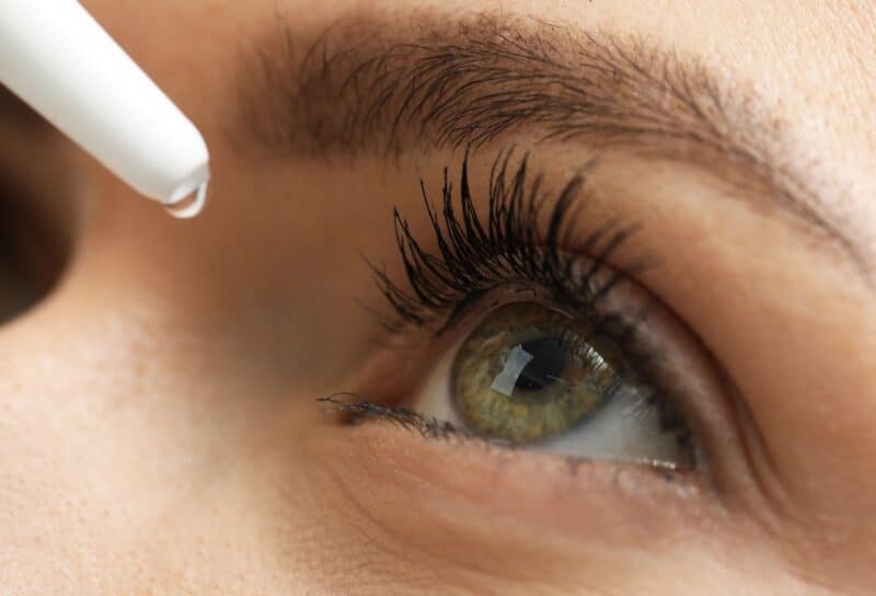 Woman applying medical eye drops