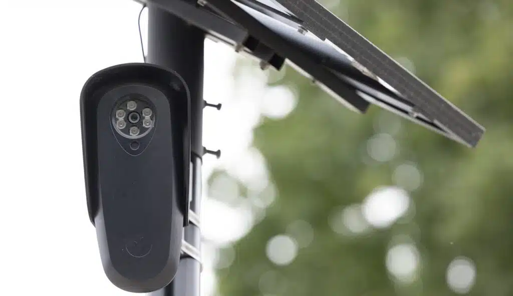 An AI Flock camera surveils a city street for car license plates.