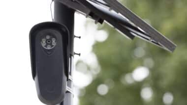 An AI Flock camera surveils a city street for car license plates.