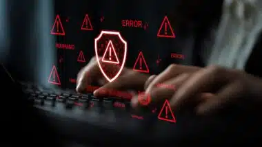Hands Typing on Keyboard with Digital Security Warnings and Alerts Displayed on Screen Representing Cybersecurity Risks and Data Protection Issues