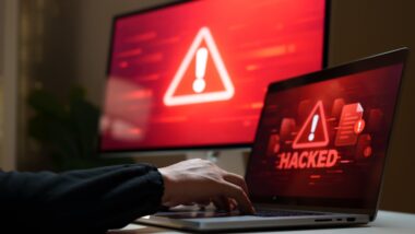 Cybersecurity threat displayed on laptop and computer screens with red warning symbols and a hacked alert