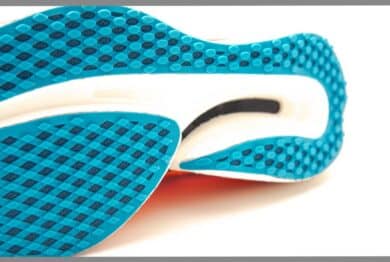 Close-up carbon plate and rigidness outsole of modern running racing shoes isolated on white background, waffle sole with carbon reinforced wave plate bottom geometry soft cushion energy return.