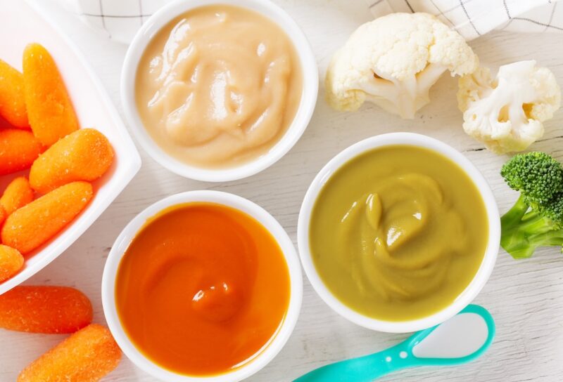 Baby food. Various kinds of bowls of fruit and vegetable puree with fresh vegetables, top view