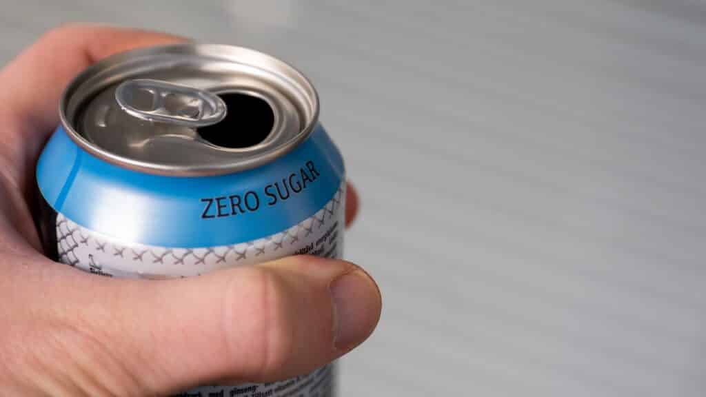 hand holding a zero sugar soda can.