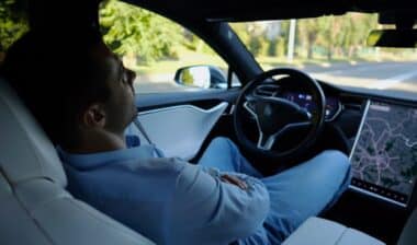 Male businessperson experience to ride an autonomous self driving electric car at urban road.