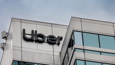 The logo and sign high up on the glass tower of the Uber offices