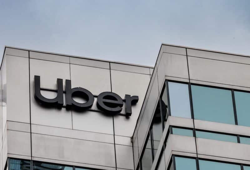 The logo and sign high up on the glass tower of the Uber offices