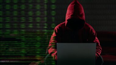 Hacking and malware concept. Hacker using laptop computer with binary code digital interface.