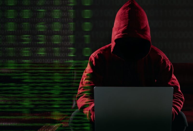 Hacking and malware concept. Hacker using laptop computer with binary code digital interface.