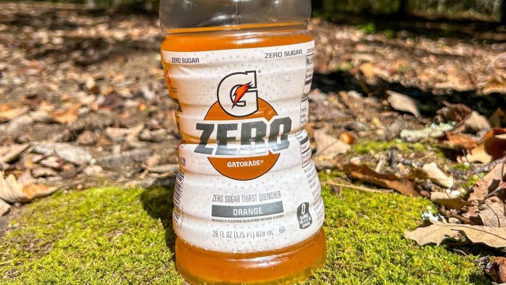 Gatorade Zero sugar orange flavored drink sitting on mossy rock with woods in background