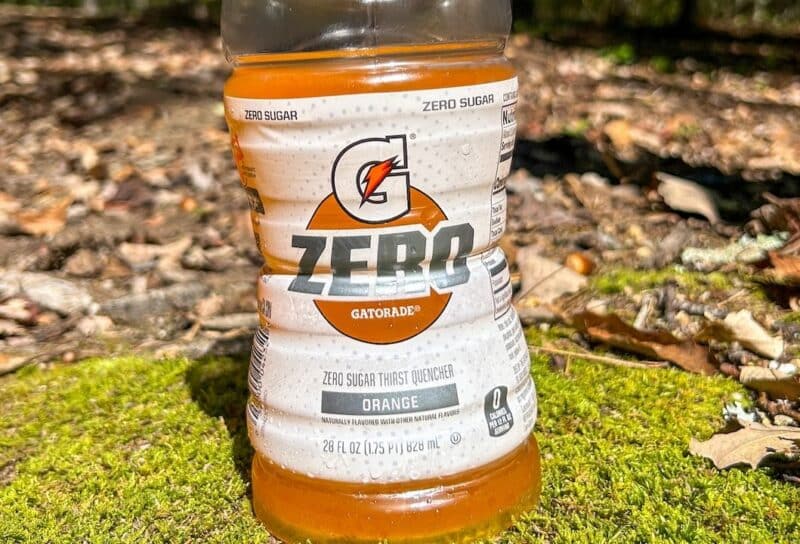 Gatorade Zero sugar orange flavored drink sitting on mossy rock with woods in background